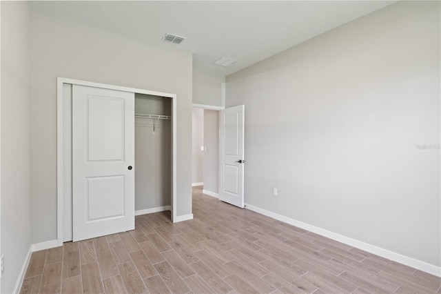 unfurnished bedroom featuring a closet, baseboards, visible vents, and light wood finished floors