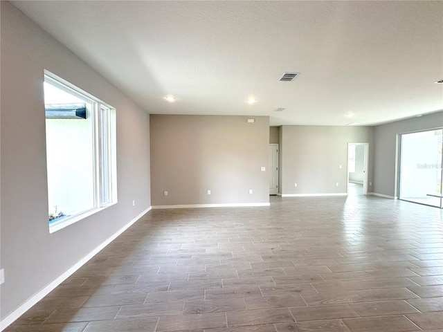 empty room with baseboards, visible vents, and wood finished floors