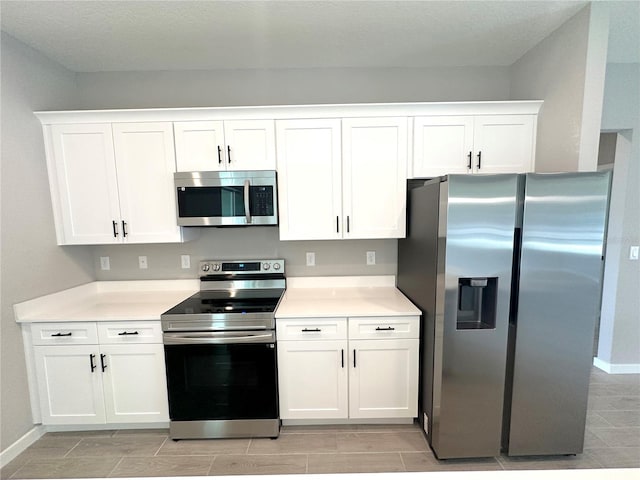 kitchen with stainless steel appliances, light countertops, and white cabinetry