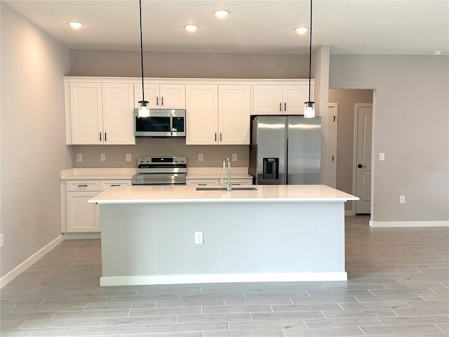 kitchen with white cabinets, an island with sink, appliances with stainless steel finishes, wood tiled floor, and a sink