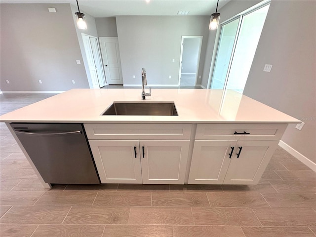 kitchen with light countertops, dishwasher, hanging light fixtures, and a sink