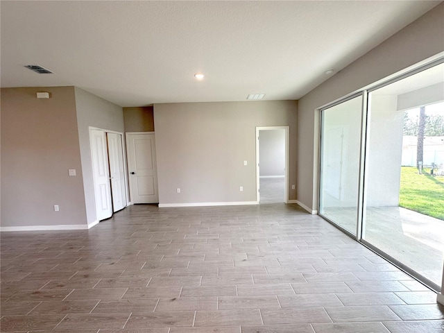 spare room with wood finish floors, visible vents, baseboards, and recessed lighting