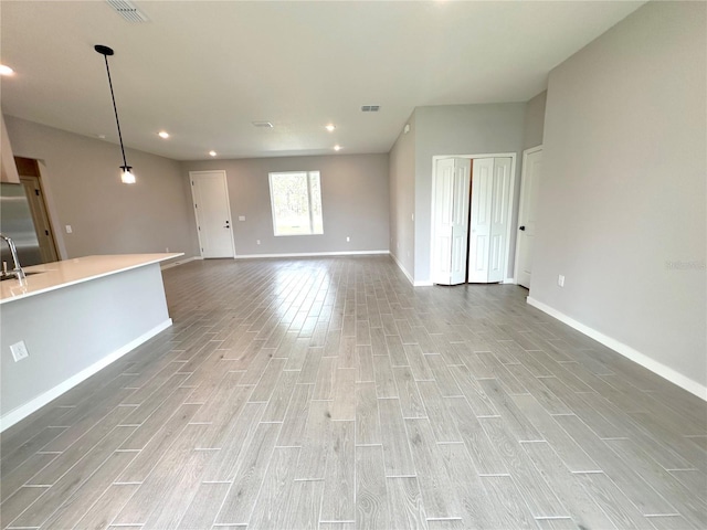 unfurnished living room with wood finish floors, visible vents, and a sink