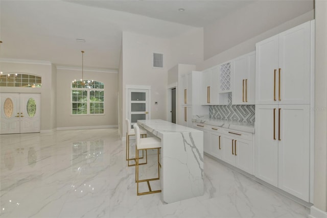 kitchen featuring light stone counters, white cabinets, an inviting chandelier, and decorative light fixtures