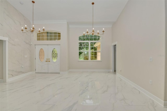 entryway with ornamental molding, a towering ceiling, and an inviting chandelier