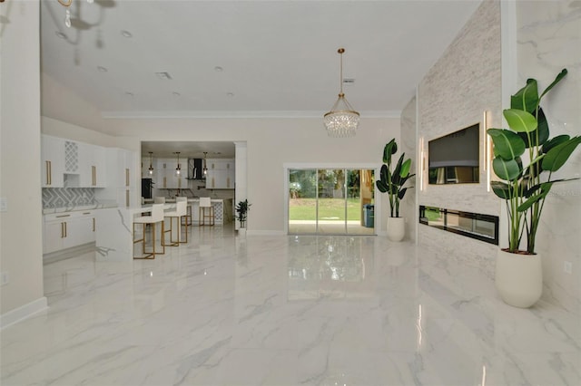 unfurnished living room with crown molding, a fireplace, and a chandelier