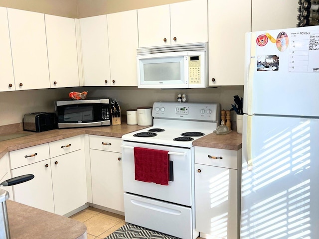 kitchen with light tile patterned floors, white appliances, and white cabinetry