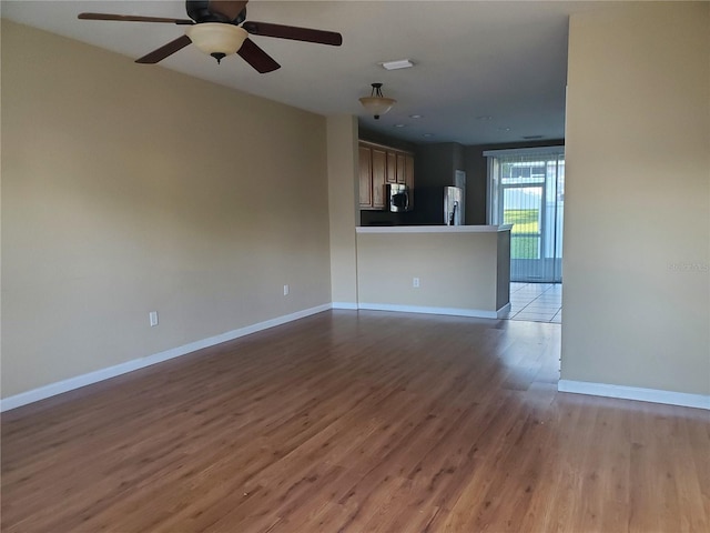 unfurnished living room featuring dark wood-type flooring and ceiling fan