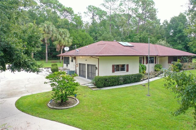 single story home with a garage, a front yard, and central air condition unit