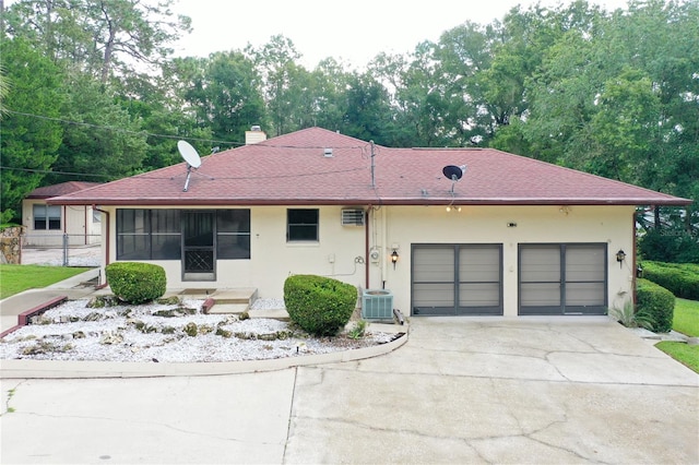 ranch-style home with a garage and central AC unit