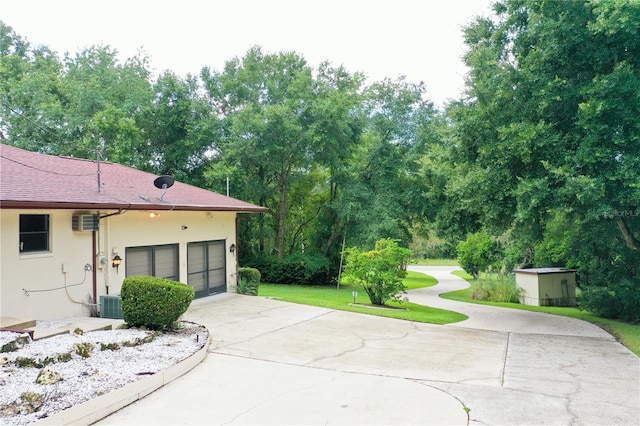 view of patio with cooling unit, a garage, and a storage shed