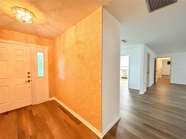 foyer entrance featuring a textured ceiling and dark wood-type flooring