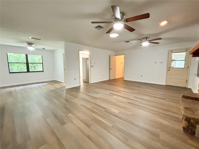 unfurnished living room featuring ceiling fan, a wealth of natural light, and light hardwood / wood-style flooring