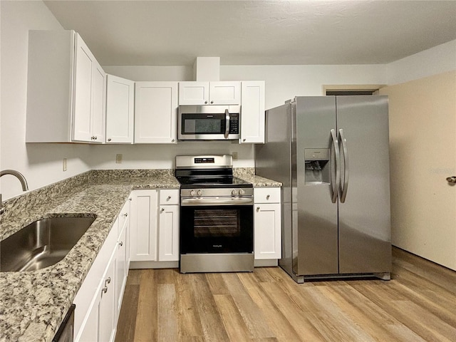 kitchen with stainless steel appliances, white cabinetry, and sink