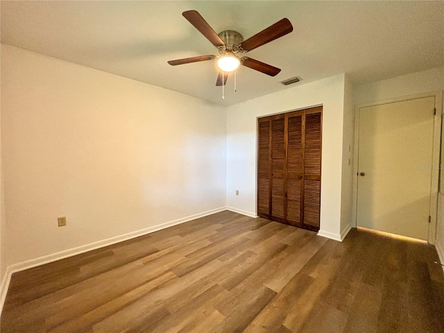 unfurnished bedroom featuring ceiling fan, a closet, and wood-type flooring