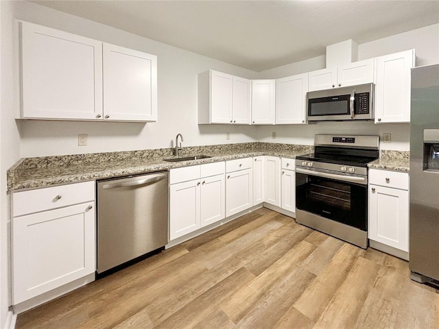 kitchen with light wood-type flooring, white cabinets, appliances with stainless steel finishes, and sink