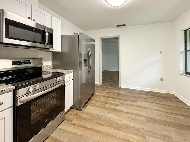21389 SW 102nd Street Rd, Dunnellon, FL 34431 - kitchen with light wood-type flooring, visible vents, white cabinetry, appliances with stainless steel finishes, and baseboards