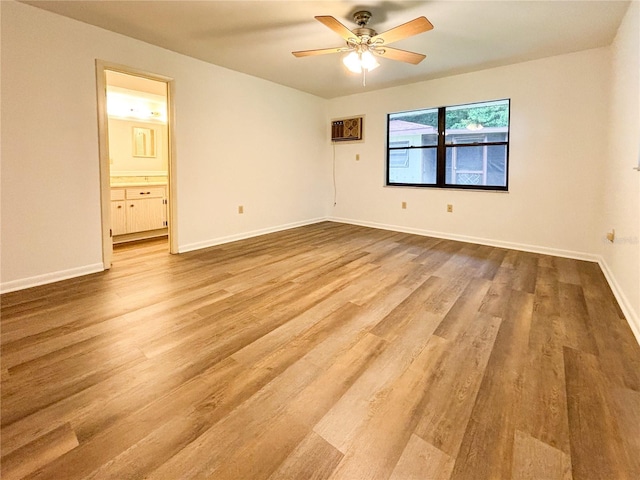 spare room with ceiling fan, light hardwood / wood-style floors, and an AC wall unit