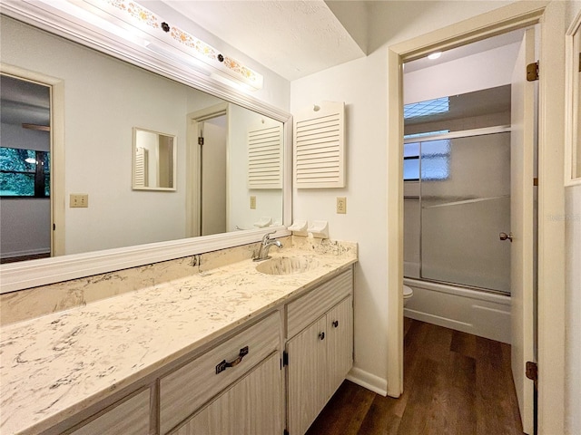 full bathroom featuring combined bath / shower with glass door, vanity, toilet, and wood-type flooring