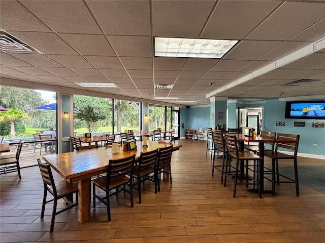 dining area featuring wood-type flooring and a drop ceiling