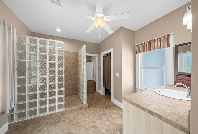 bathroom with tiled shower, sink, and ceiling fan