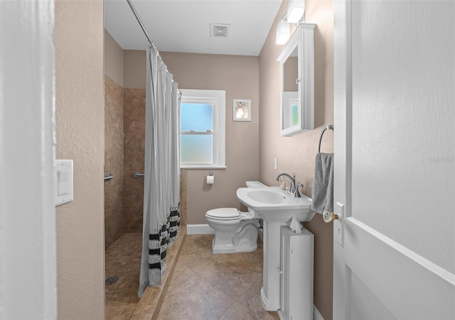 bathroom with a shower with curtain, sink, tile patterned flooring, and toilet