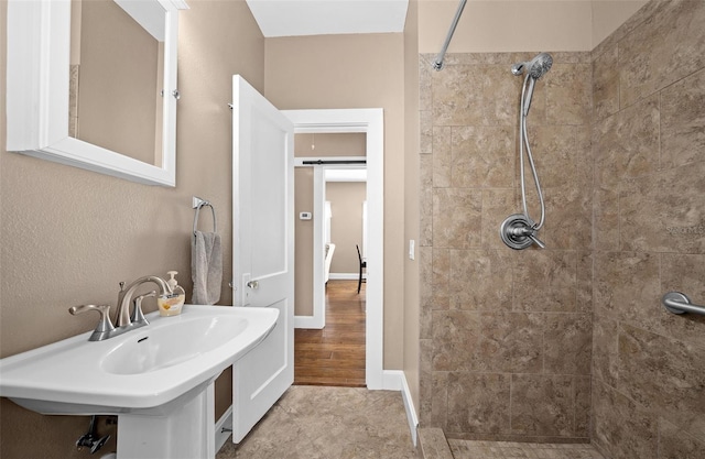 bathroom with hardwood / wood-style flooring, sink, and tiled shower