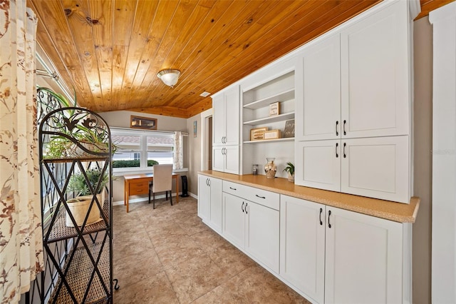 kitchen with built in desk, light tile patterned flooring, white cabinetry, vaulted ceiling, and wooden ceiling