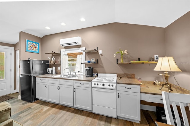 kitchen featuring an AC wall unit, white cabinetry, light hardwood / wood-style floors, and white range oven