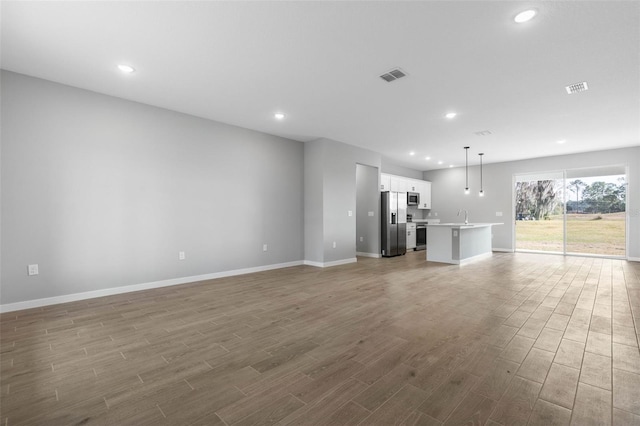 unfurnished living room with wood-type flooring and sink