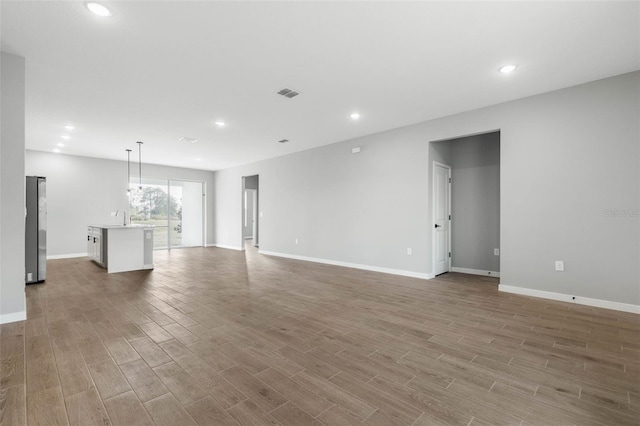 unfurnished living room with sink and light hardwood / wood-style floors