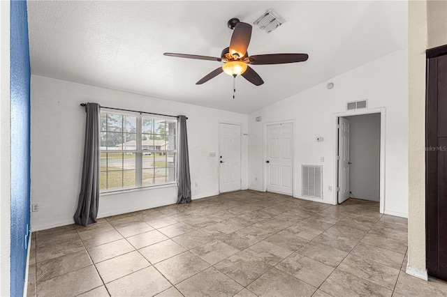 tiled spare room with lofted ceiling, ceiling fan, and a textured ceiling