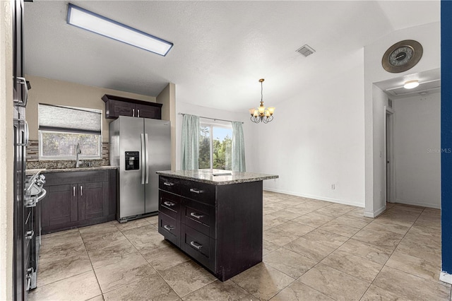 kitchen featuring light stone counters, sink, pendant lighting, a kitchen island, and stainless steel fridge with ice dispenser