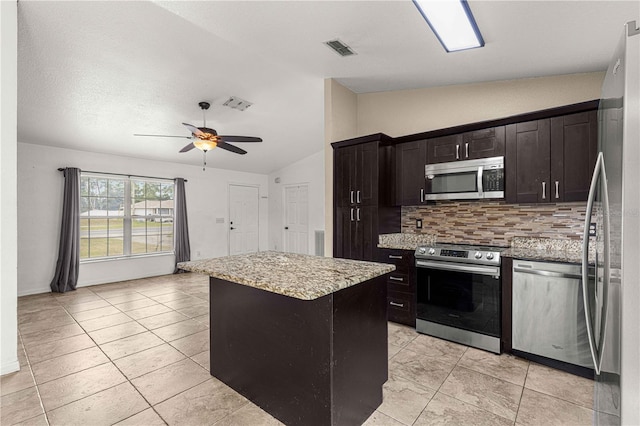 kitchen with lofted ceiling, appliances with stainless steel finishes, a center island, and ceiling fan