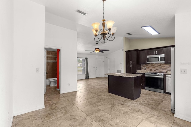 kitchen with ceiling fan with notable chandelier, appliances with stainless steel finishes, a center island, hanging light fixtures, and lofted ceiling