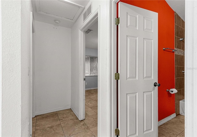 hallway featuring a textured ceiling and light tile patterned flooring