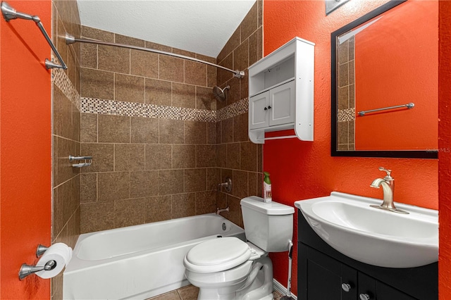 full bathroom featuring tile patterned floors, toilet, tiled shower / bath combo, vanity, and a textured ceiling