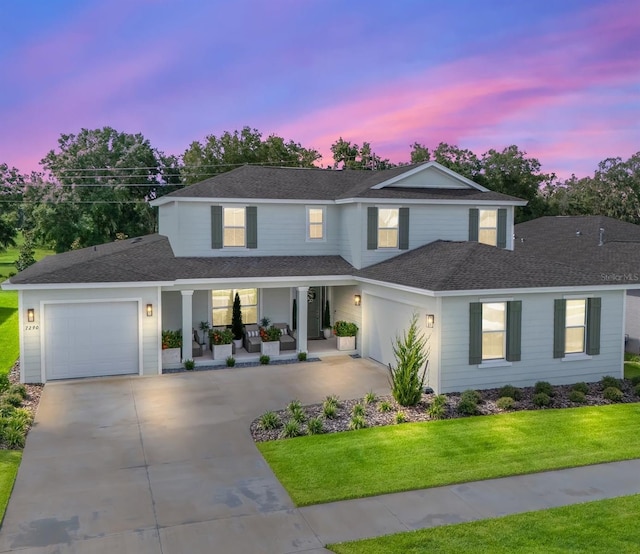 view of front of home featuring covered porch, a lawn, and a garage