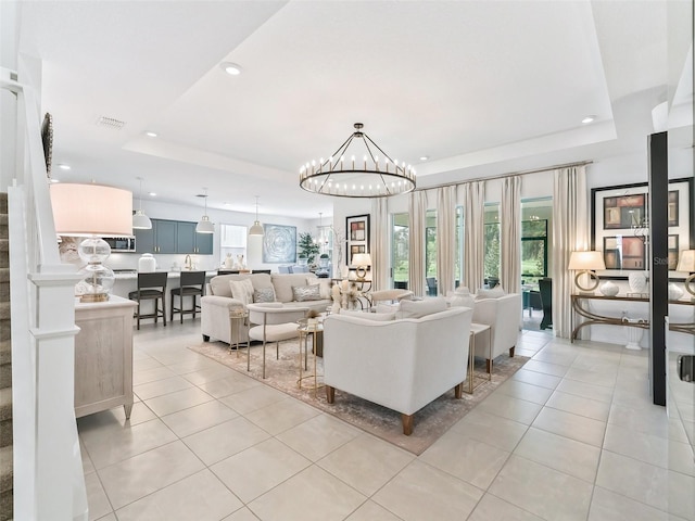 living room featuring a raised ceiling, light tile patterned floors, and a chandelier