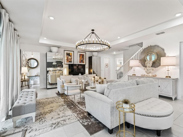 tiled living room featuring a raised ceiling and a notable chandelier