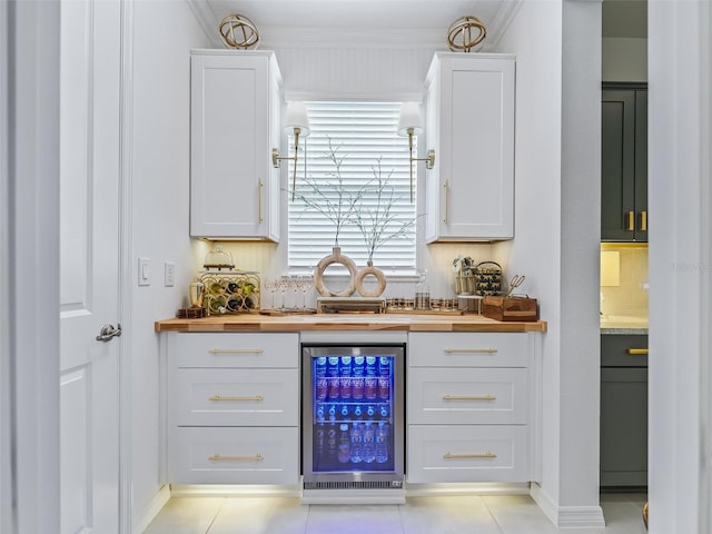 bar with wooden counters, beverage cooler, light tile patterned floors, and white cabinets