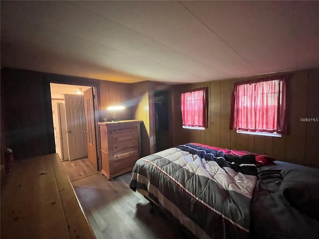 bedroom featuring hardwood / wood-style flooring and wooden walls