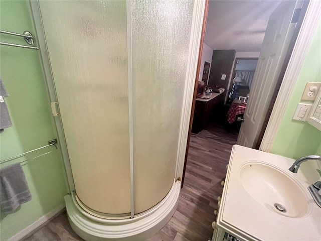 bathroom featuring wood-type flooring, a shower with door, and vanity