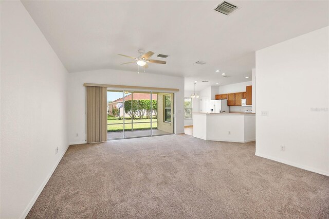 unfurnished living room featuring ceiling fan, light colored carpet, and vaulted ceiling