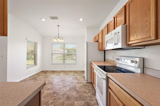 kitchen with vaulted ceiling, decorative light fixtures, white appliances, and a chandelier