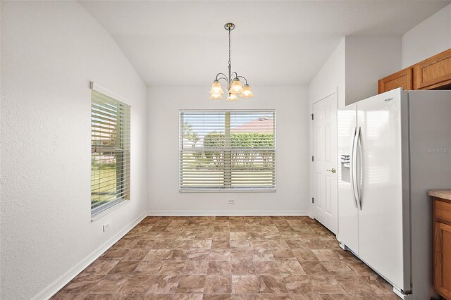 kitchen featuring a chandelier, pendant lighting, white fridge with ice dispenser, and vaulted ceiling