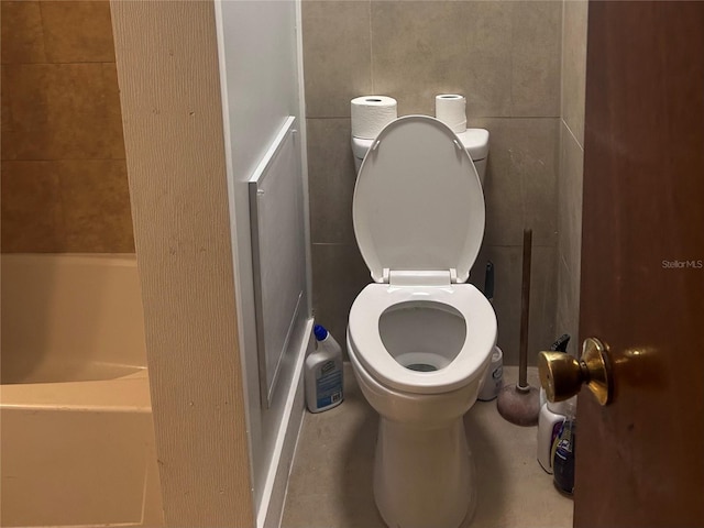 bathroom featuring toilet and tile walls