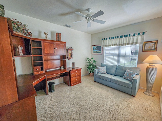 carpeted office space with a textured ceiling and ceiling fan