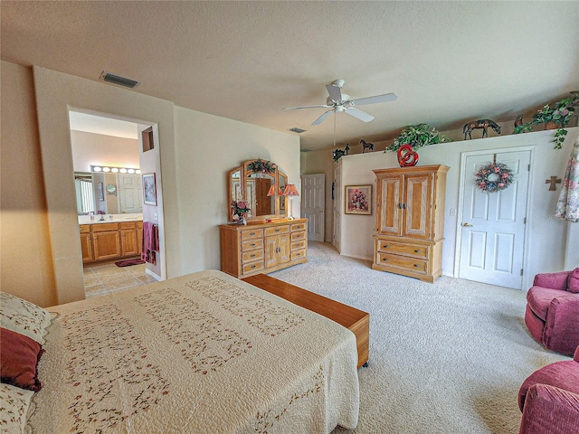 bedroom featuring ceiling fan, light colored carpet, connected bathroom, and a textured ceiling