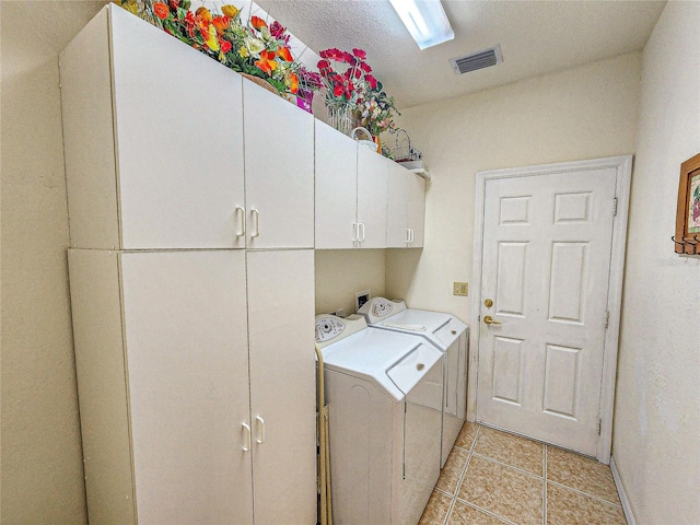 washroom featuring separate washer and dryer, a textured ceiling, cabinets, and light tile patterned floors